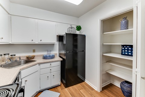 A kitchen with white cabinets and a black fridge.