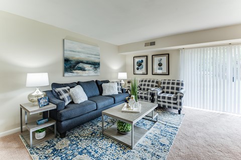 A living room with a blue sofa, a coffee table, and a painting on the wall.