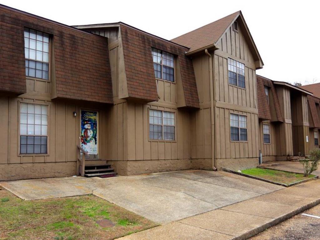 A building with brown and tan exterior and a small front yard.