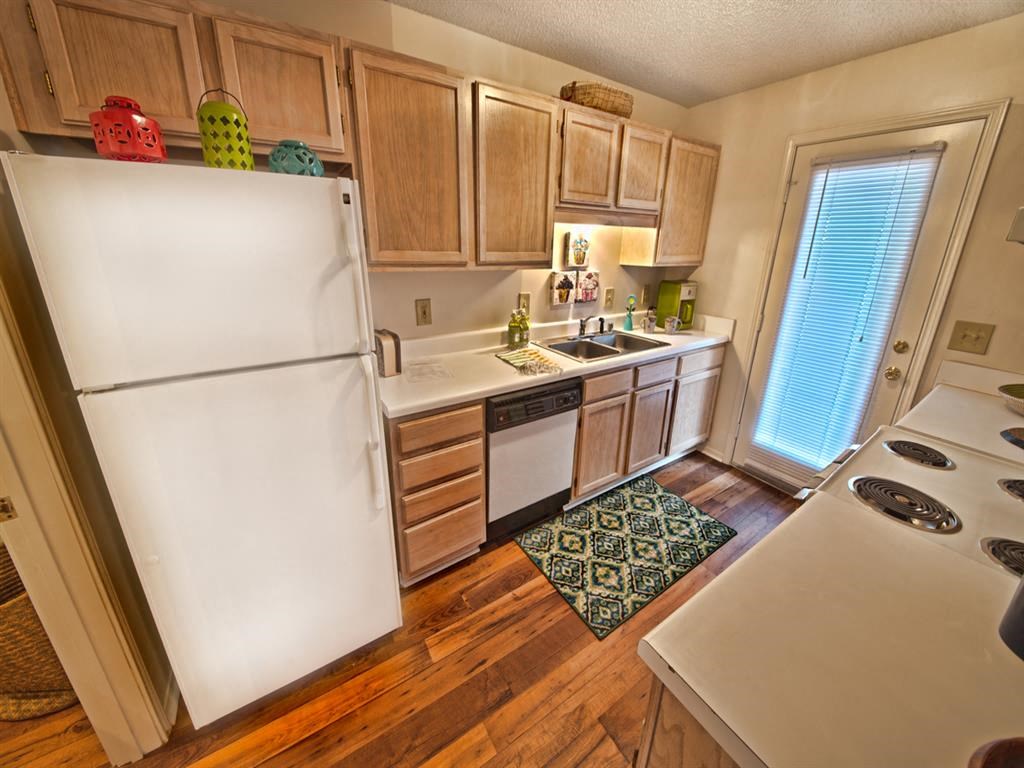 a kitchen with white appliances and wooden floors