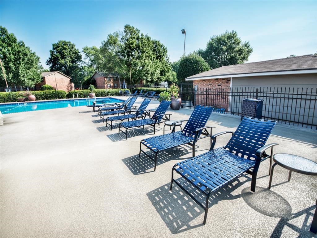 a pool with blue lounge chairs and tables around it