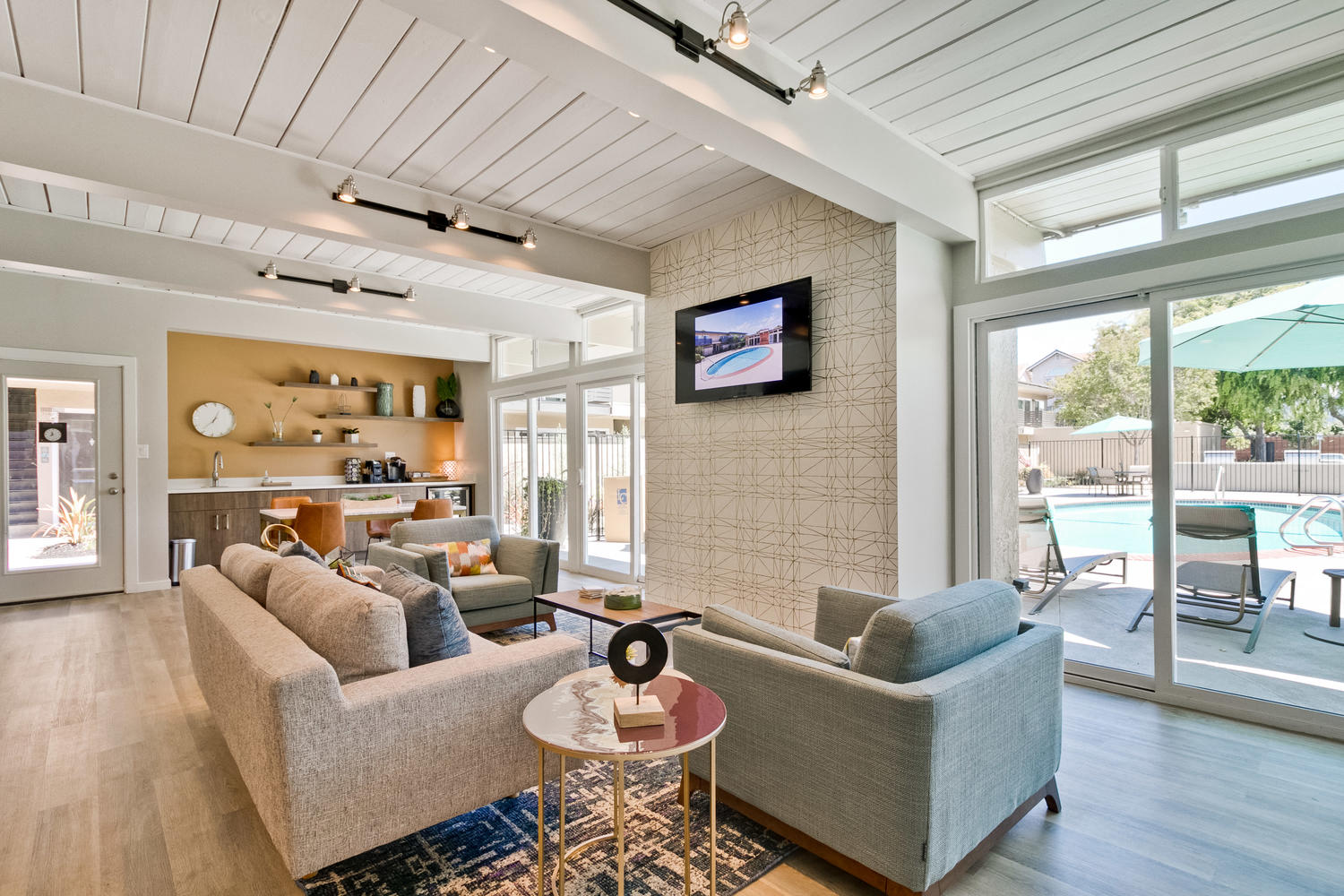 A living room with a grey couch and a television on the wall.