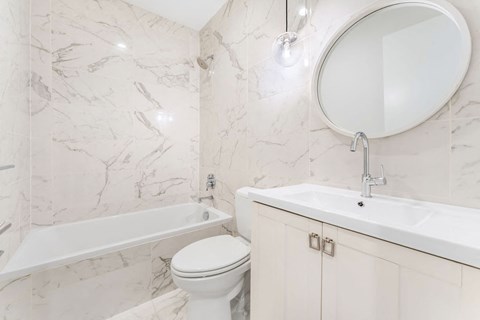A white toilet sits next to a sink in a marble bathroom.