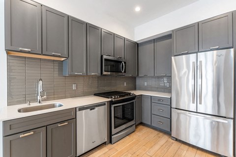 A modern kitchen with stainless steel appliances and wooden floors.
