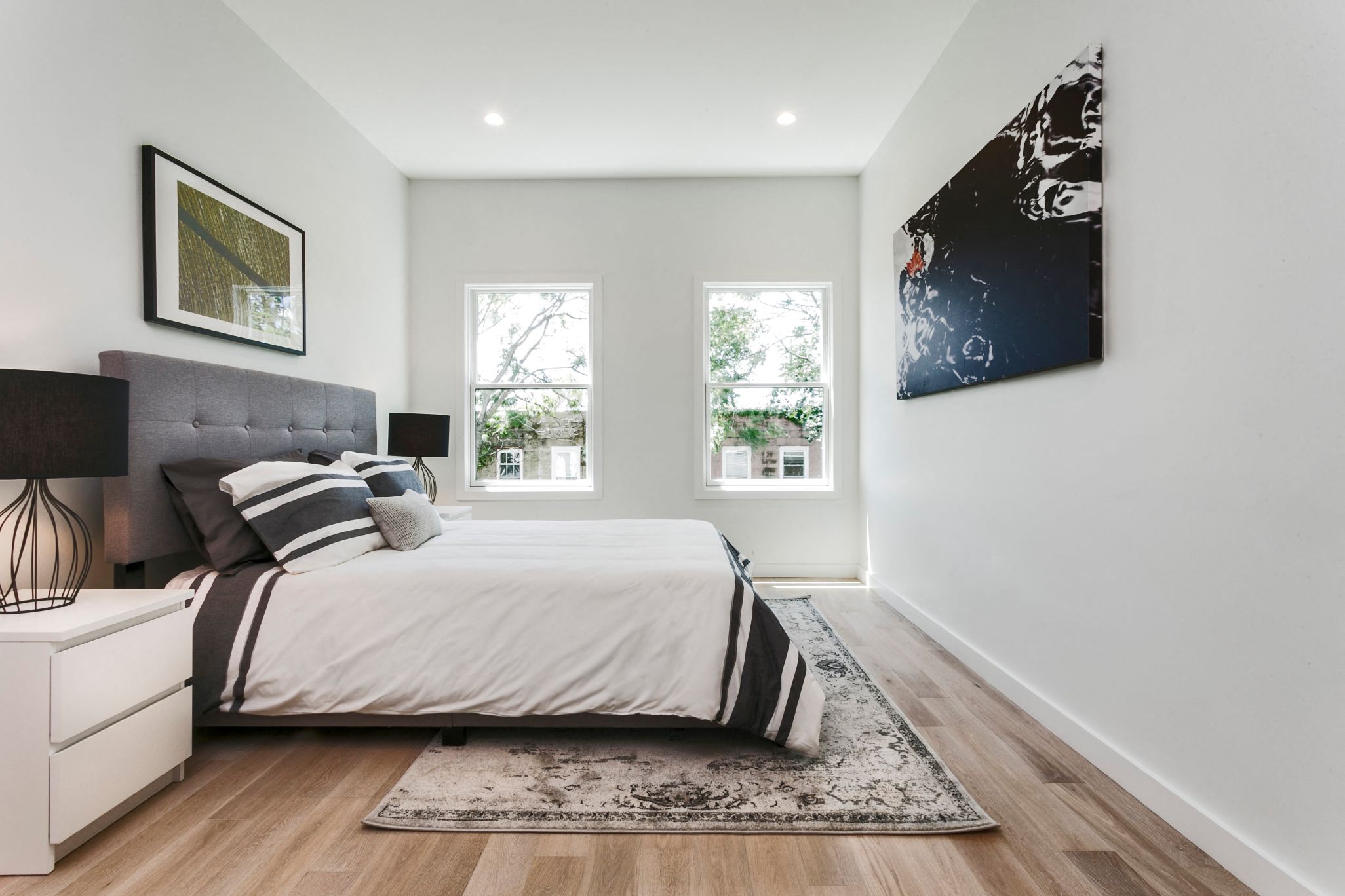 A bedroom with a large bed and a painting on the wall.