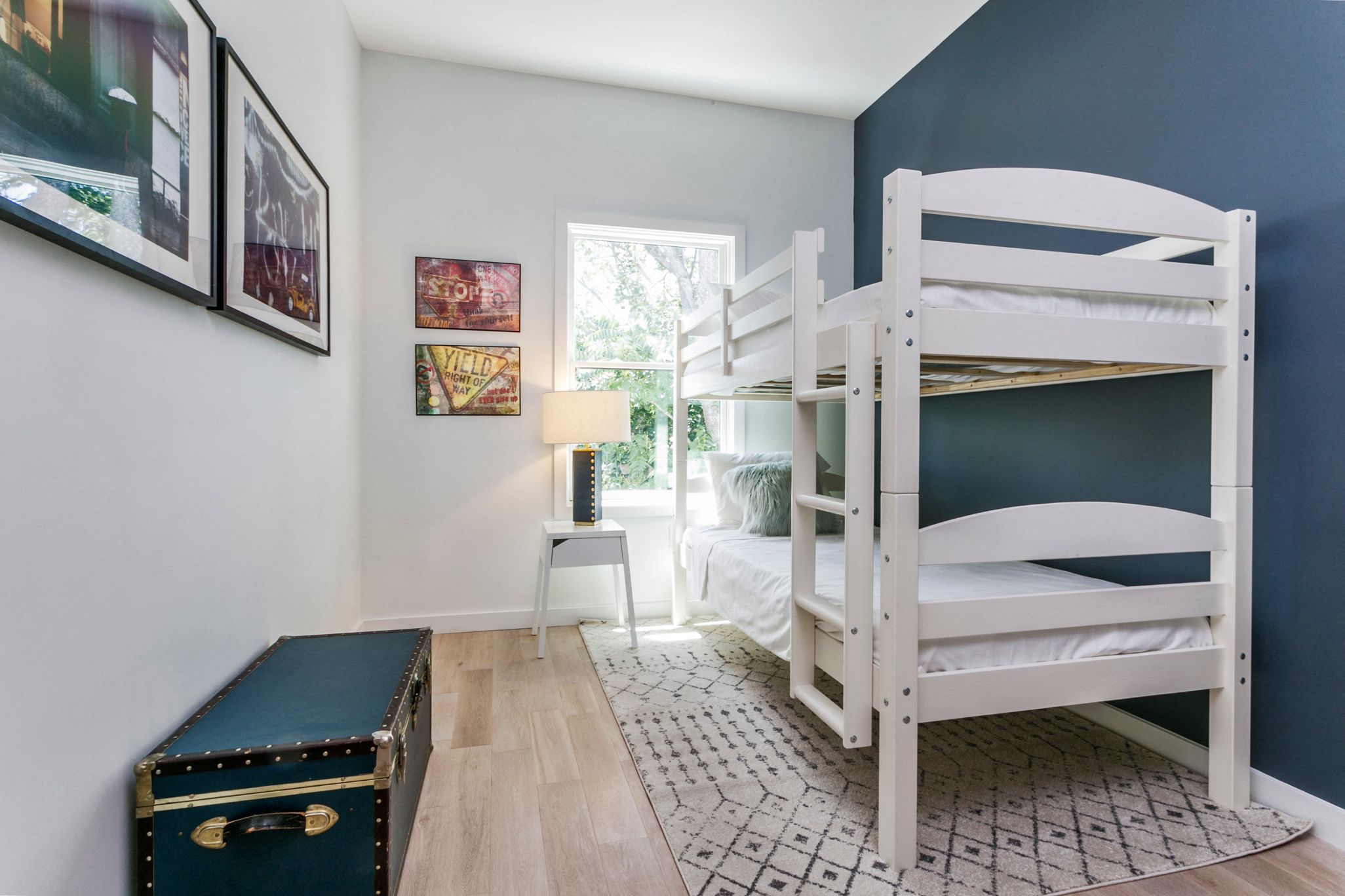 a bunk bed and a trunk in a bedroom with a window