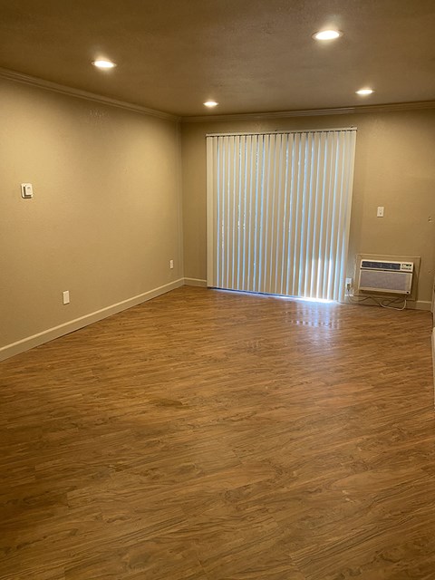 an empty living room with a wooden floor and a large window with a curtain