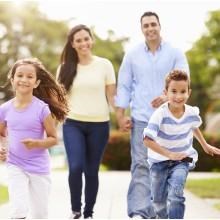 A family of four is running together in a park.