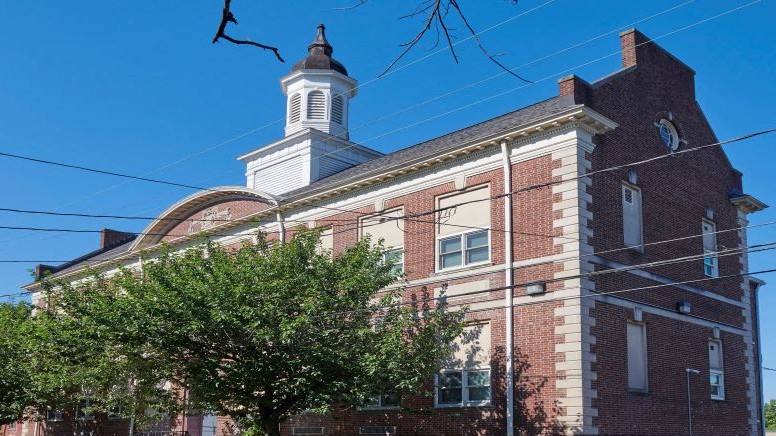 A red brick building with a white steeple and a clock on the side.