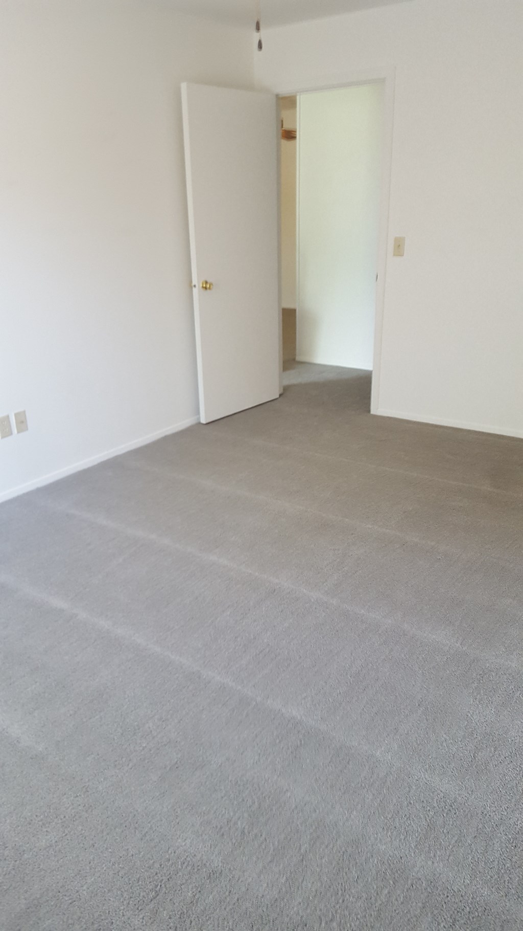 an empty living room with a gray carpet and white walls