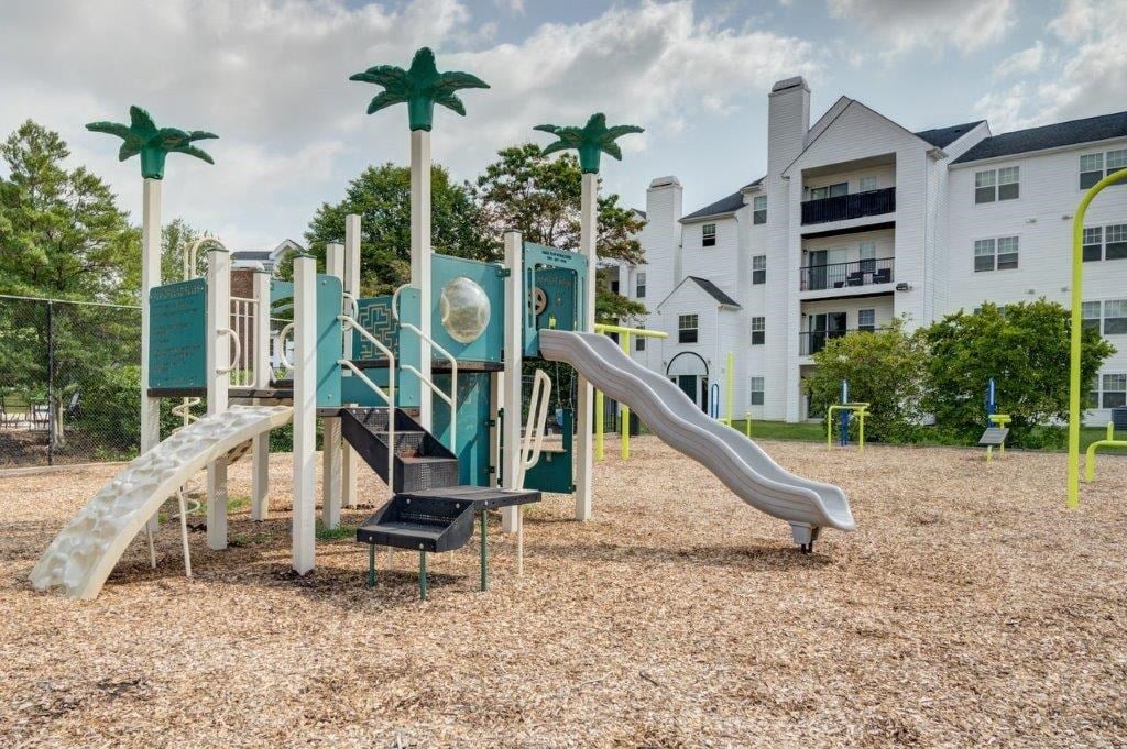 a playground with a jungle gym and slides in front of an apartment building