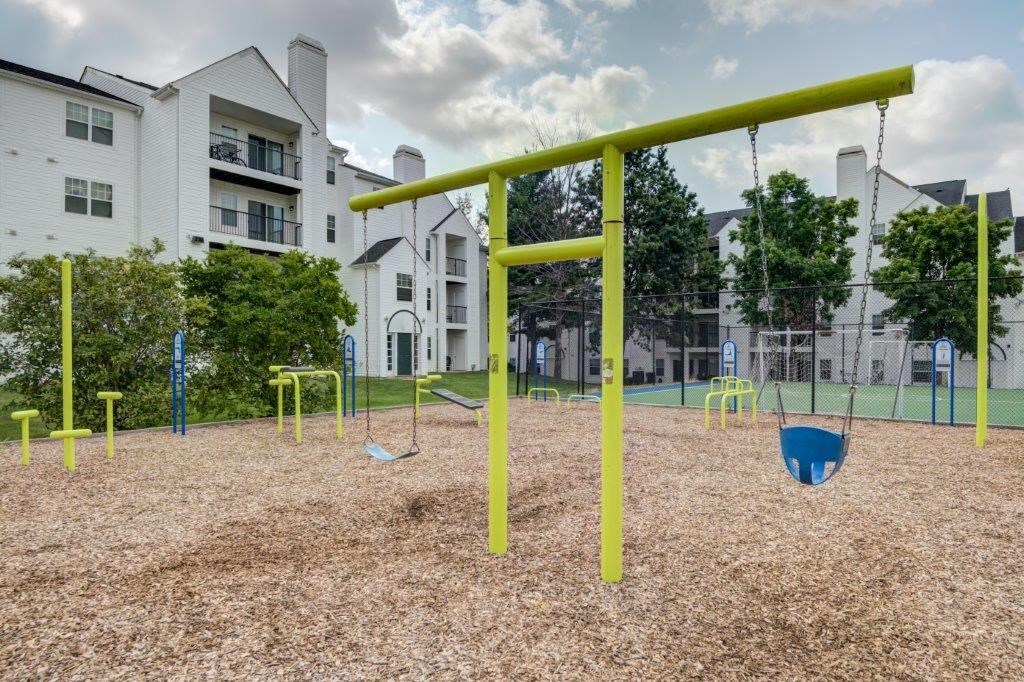 a playground with swings and a swing set in front of apartment buildings