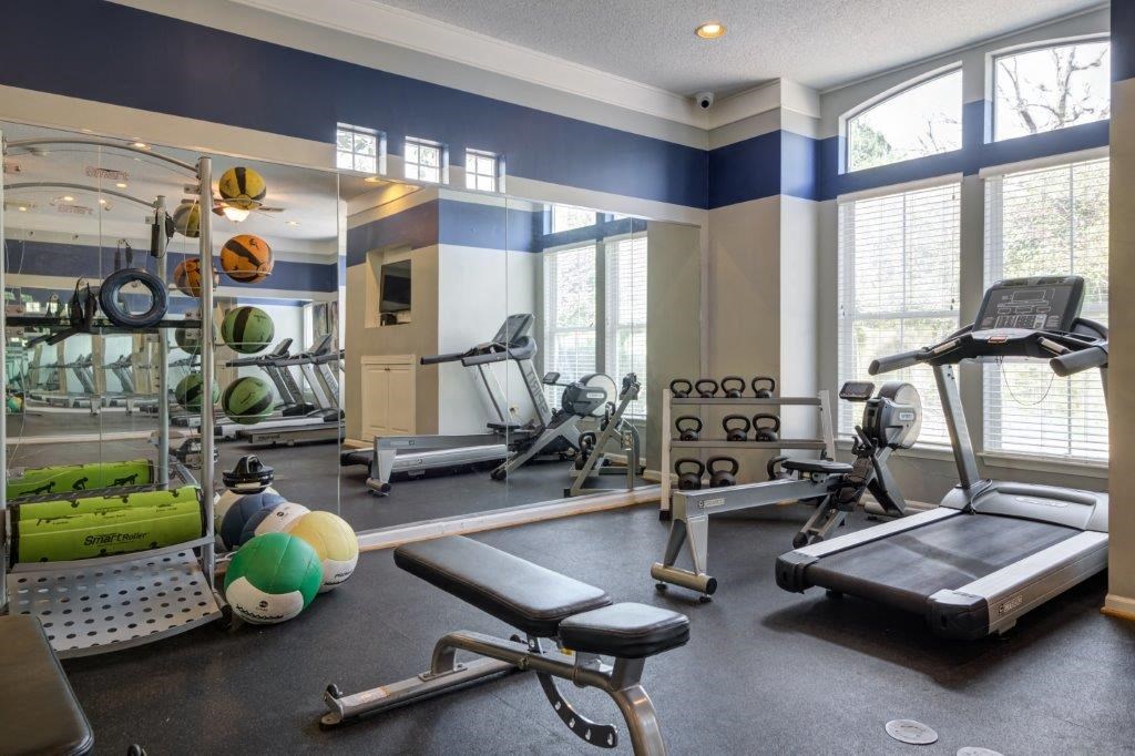 a gym with weights and other equipment and windows
