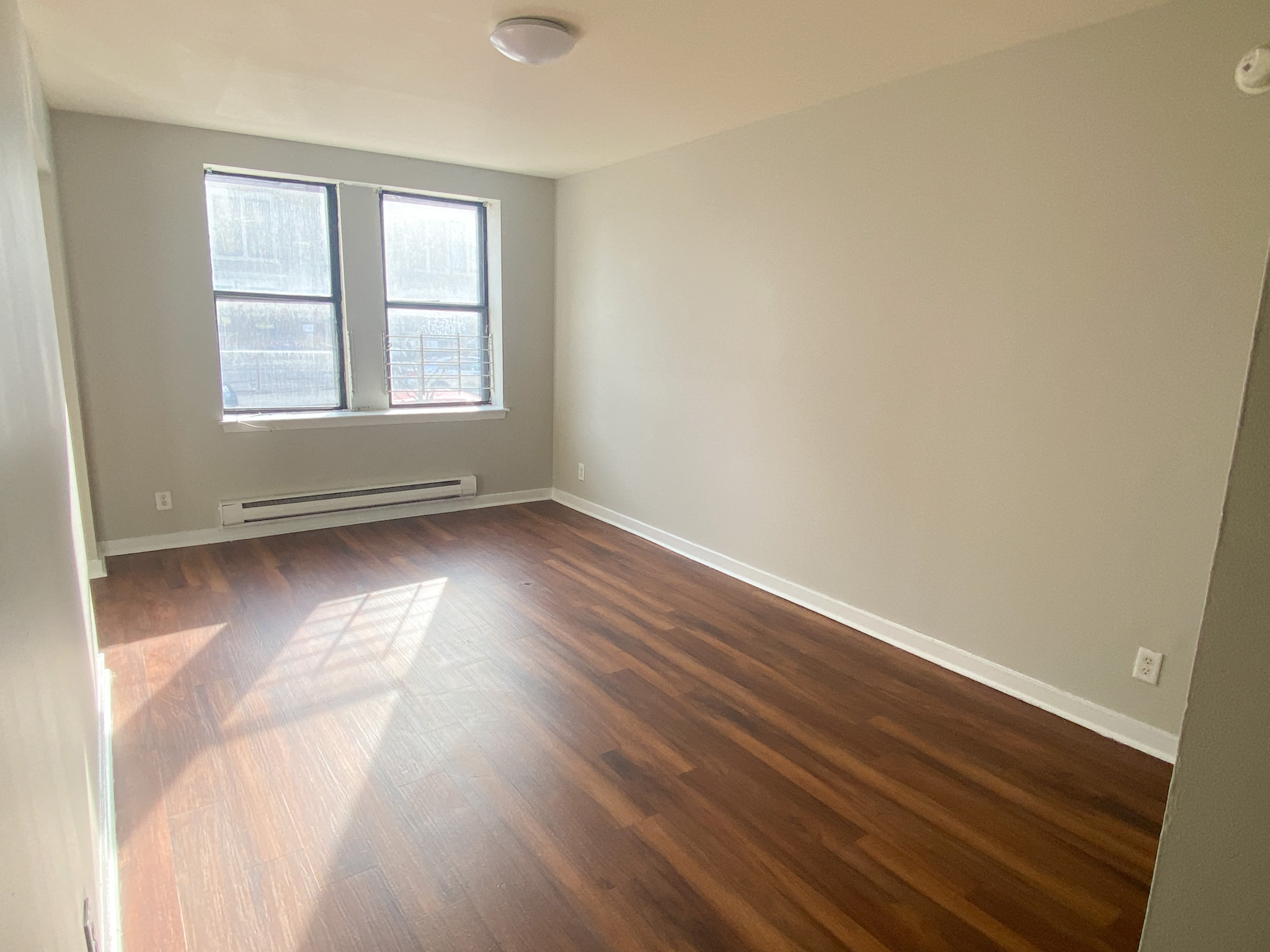 an empty living room with wooden floors and a window