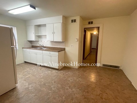 a kitchen with white cabinets and a sink and a refrigerator