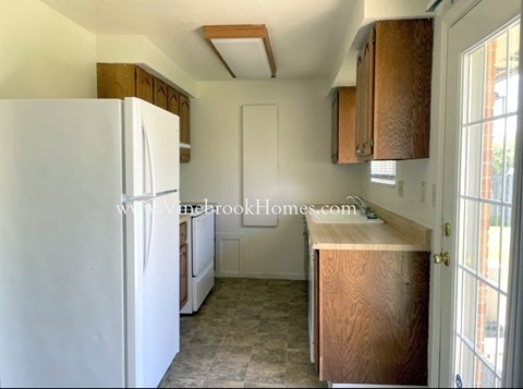 a small kitchen with a white refrigerator and a window