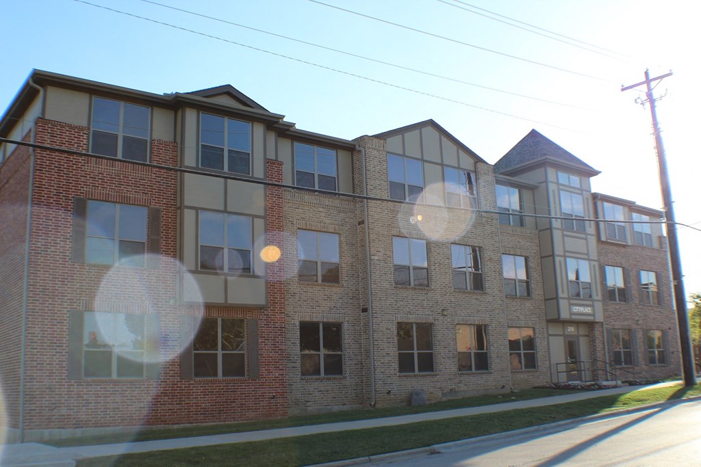 A red brick building with a white trim around the windows at City Place Apartments Denton, TX