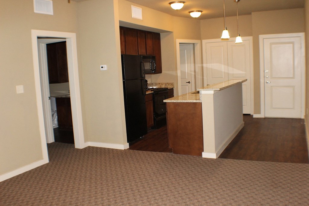 A kitchen with a black refrigerator and white cabinets at City Place Apartments Denton, TX, 76201