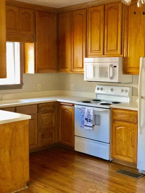 A kitchen with wooden cabinets and a white stove.