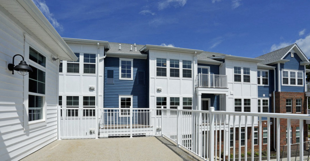 a row of blue and white condominiums behind a white fence