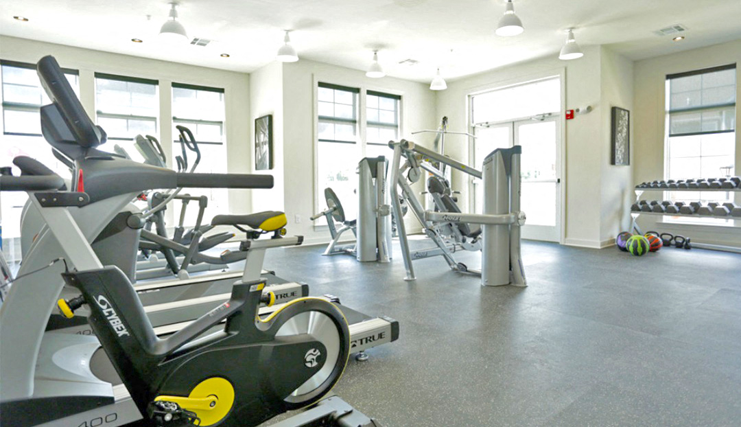 a gym with cardio equipment and weights on the floor
