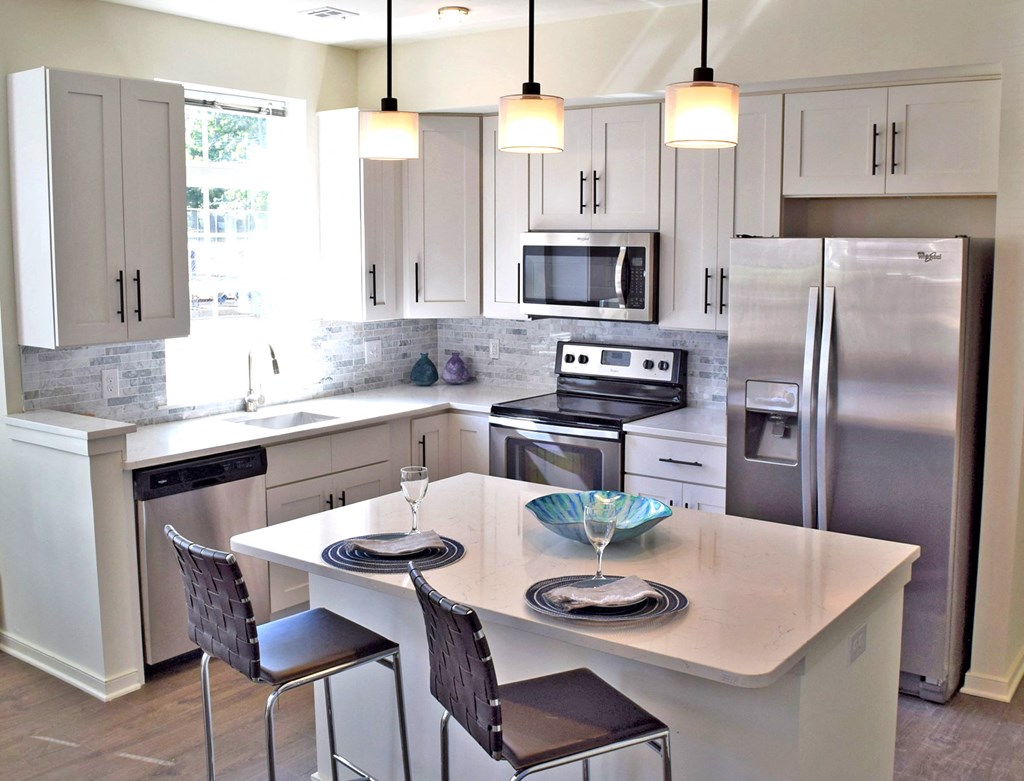 a white kitchen with stainless steel appliances and a white island