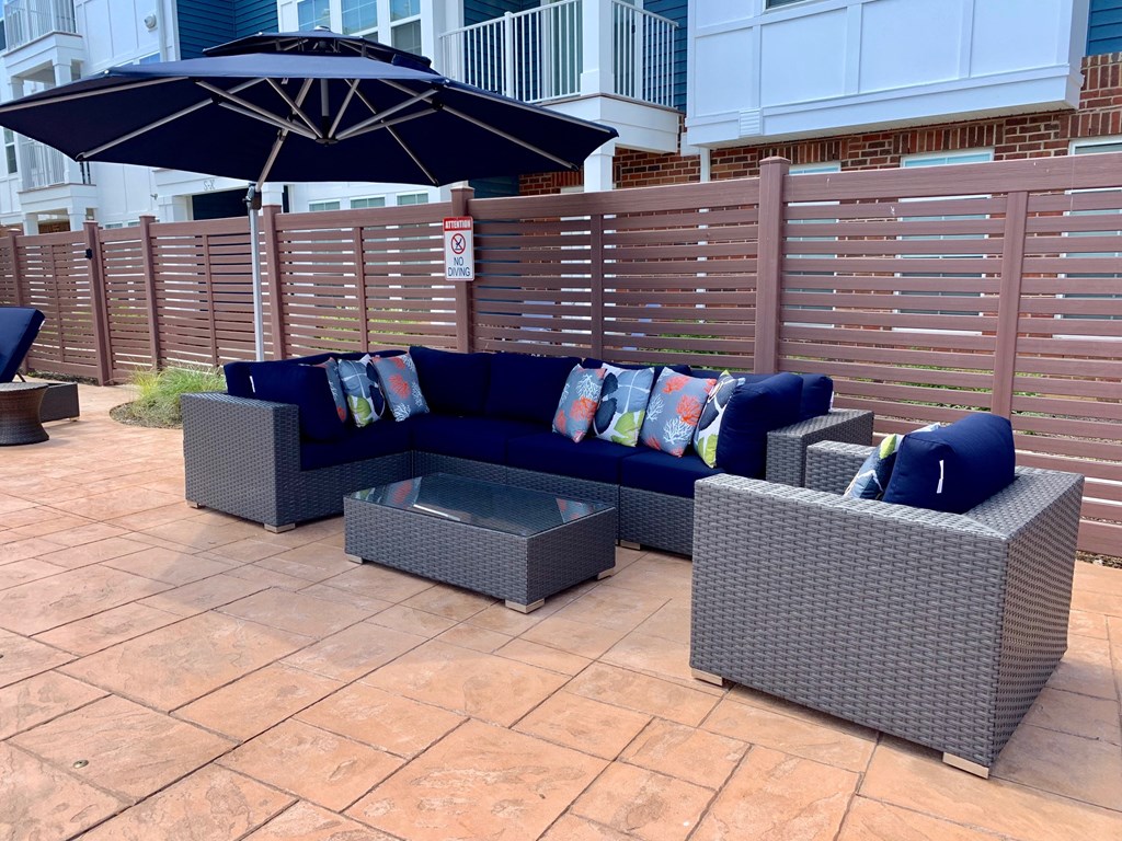 a patio with couches and chairs and umbrellas