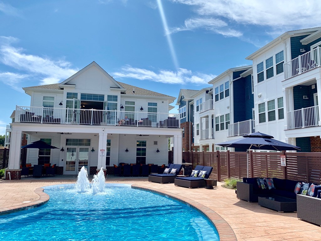 a pool with a fountain in front of an apartment building
