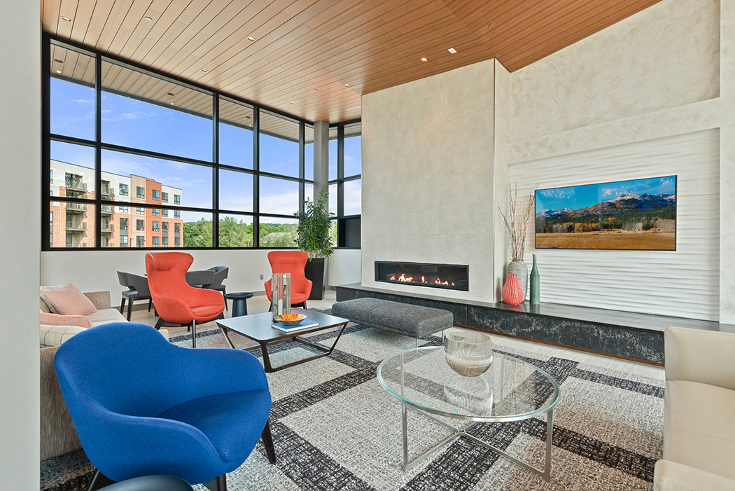 A private conference room with flexible work spaces, a modern fireplace, large windows, and comfortable seating lounges. at Keva Flats, Exton, 19341