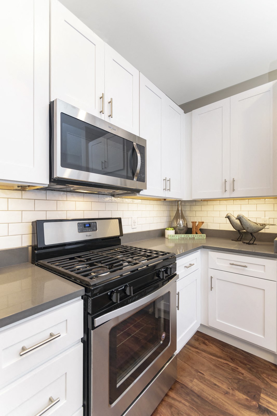 A kitchen corner with stainless steel appliances, quartz countertops, white cabinets, and a subway tile backsplash. at Keva Flats, Exton, 19341