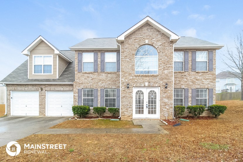 a brick house with white garage doors and a lawn