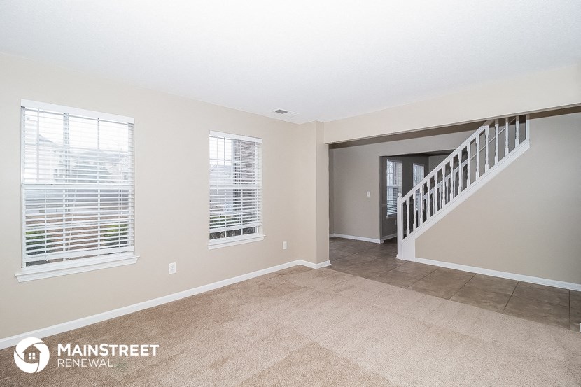 the living room and entryway of a renovated house with a staircase