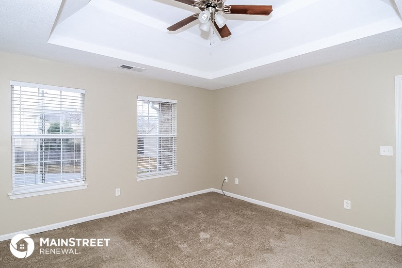the master bedroom has a ceiling fan and a carpeted floor