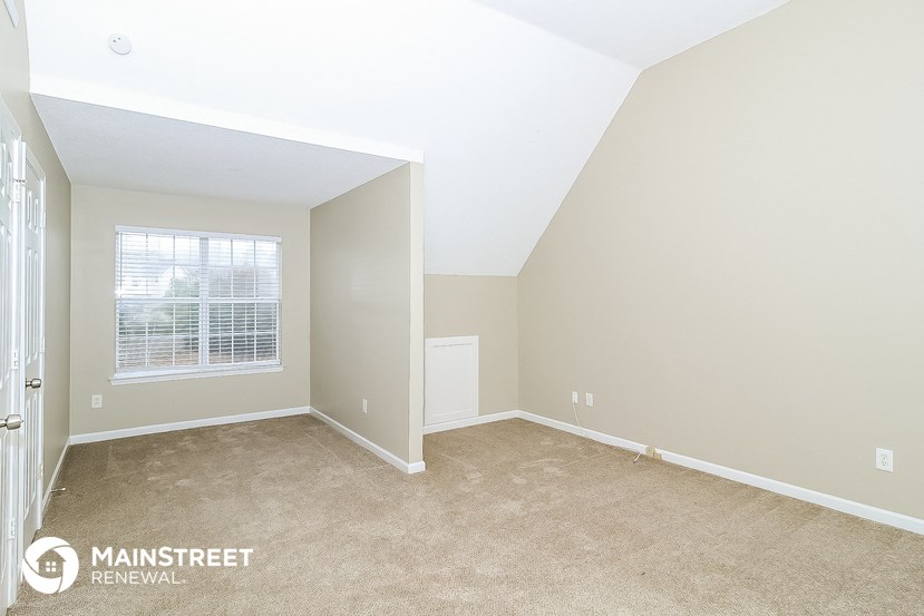 the bedroom of a rental home with carpet and a window