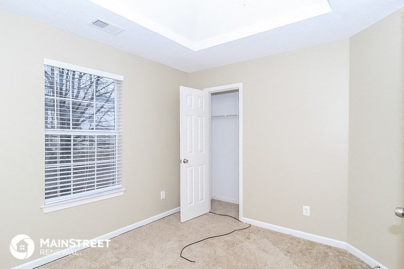 a bedroom with a door and a window and a carpeted floor