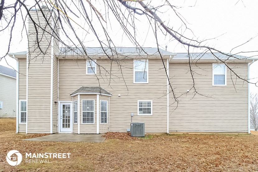 the front of a house with a yard and tree