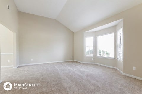 the living room of a new home with carpet and large windows