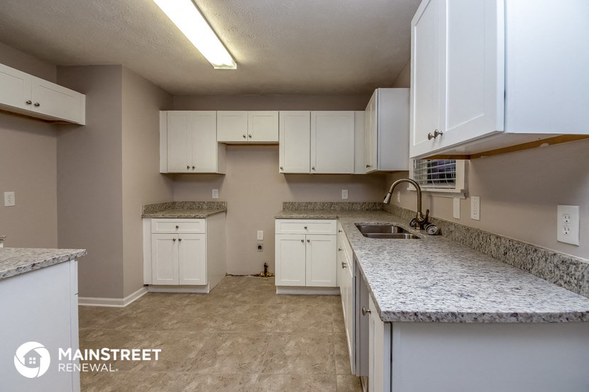 a kitchen with white cabinets and granite counter tops