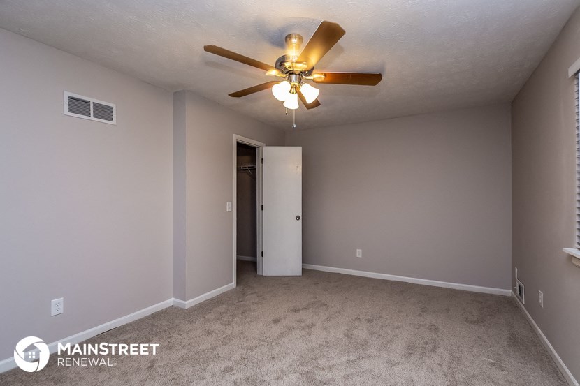 the spacious living room with ceiling fan and carpet