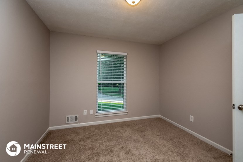 the bedroom of a house with a window and carpet