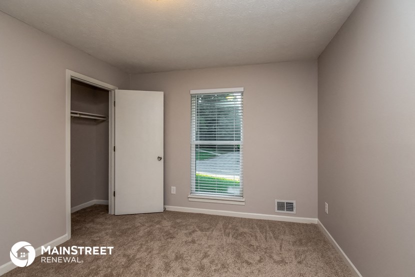 a bedroom with a large window and a door to a closet