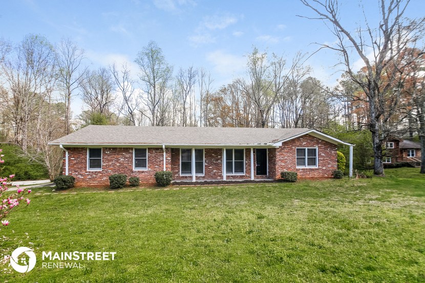 a brick home with a green lawn and trees