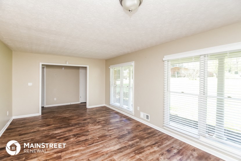 an empty living room with wood flooring and large windows
