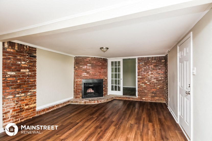 a living room with a brick fireplace and wooden floors