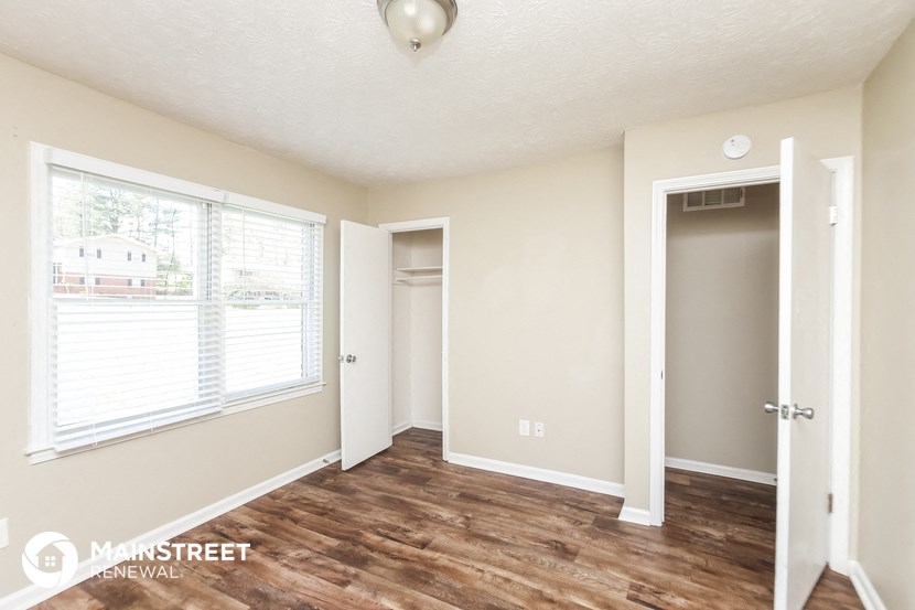 a living room with a hardwood floor and a door to a closet