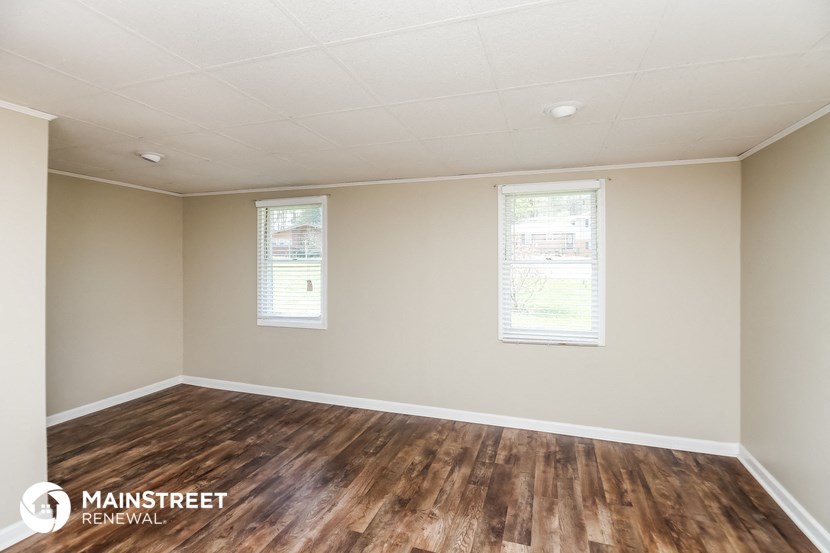 the spacious living room with wood floors and white walls
