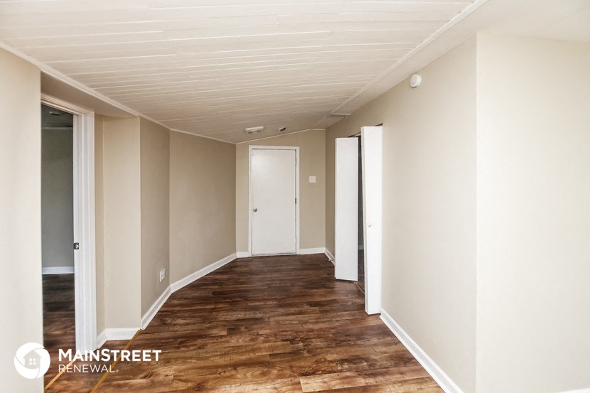 an empty hallway with wood floors and white walls