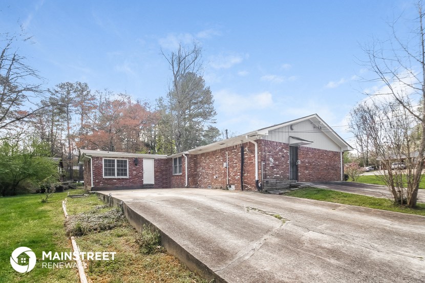 a small brick house with a road in front of it