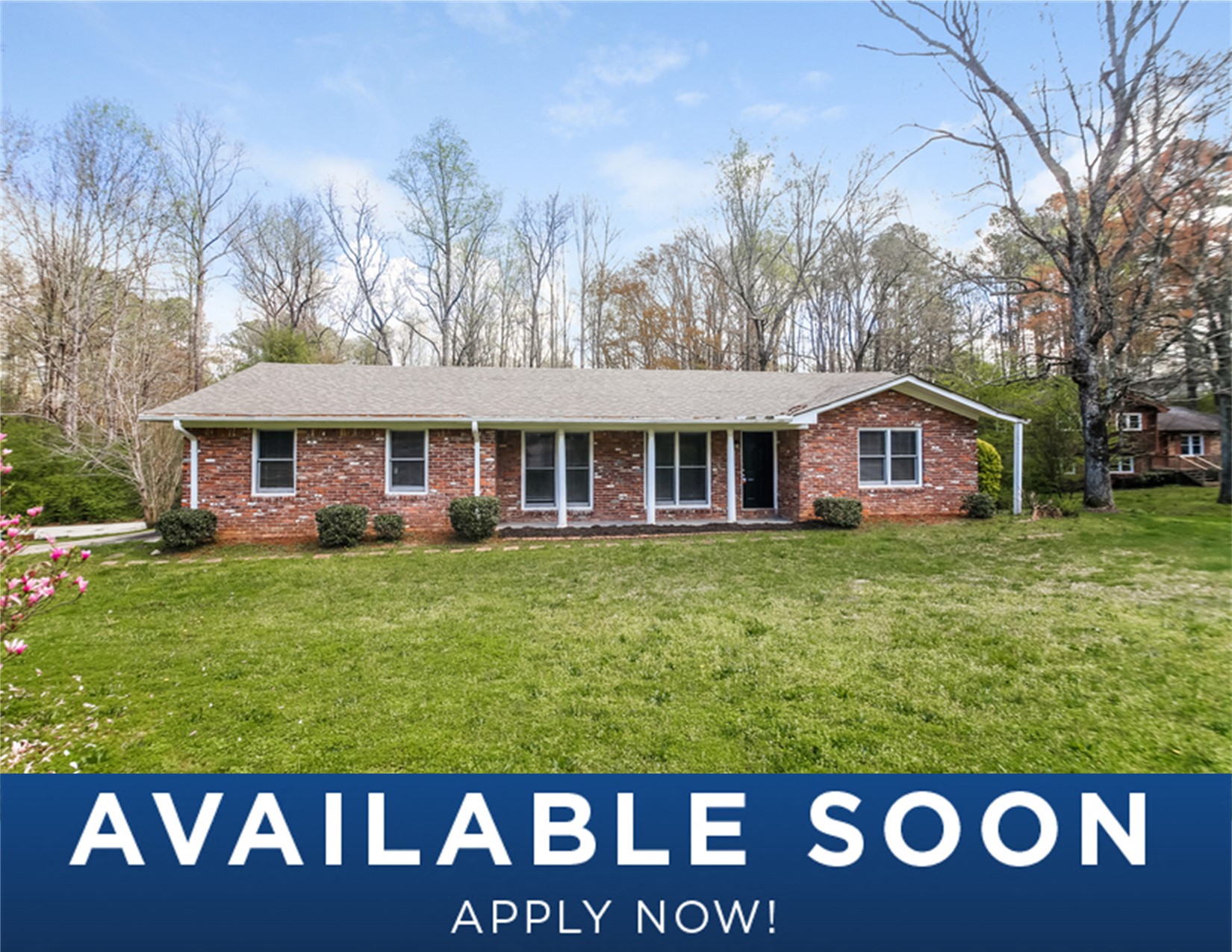 a small brick house with a green lawn and trees