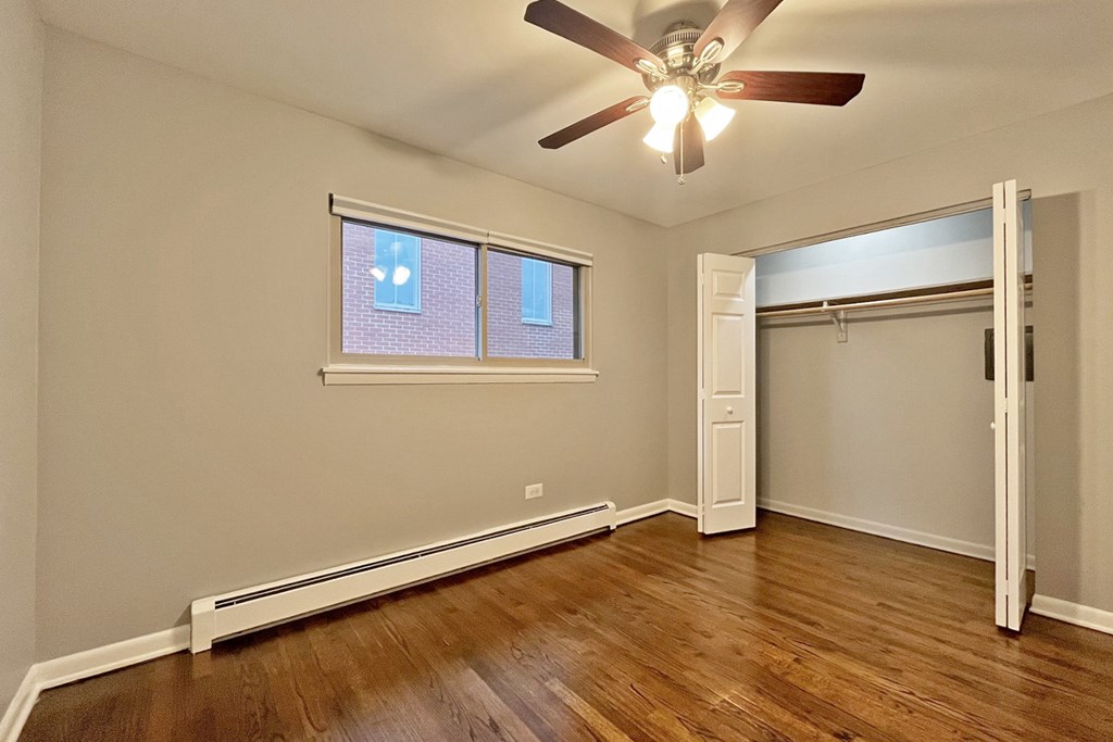 A room with a ceiling fan and a window with blinds.